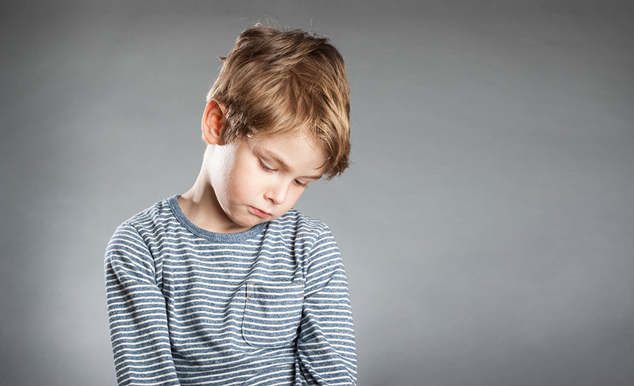 young-boy-looking-sad-in-striped-shirt